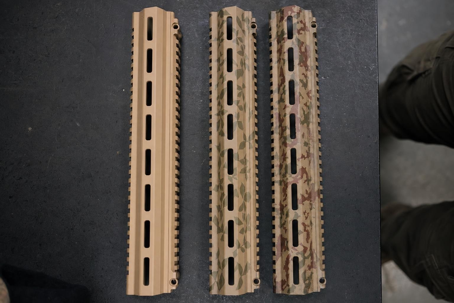 Three airsoft rifle handguards showing the stages of a camo paint job