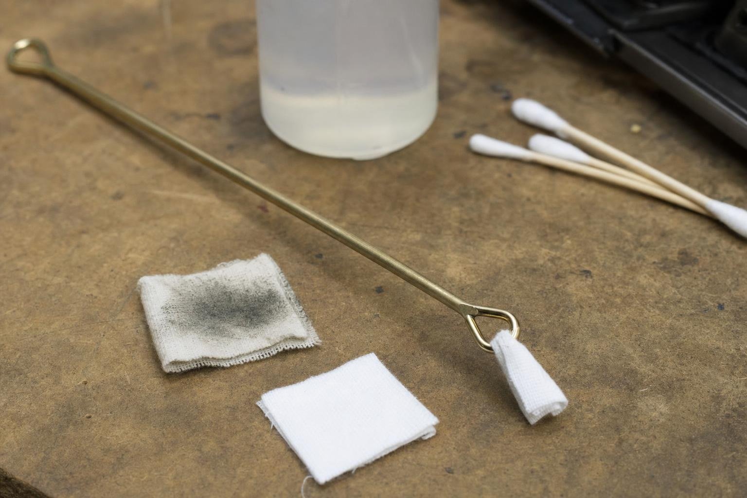 Cleaning rod with a microfibre patch beside a dirty used patch and a clean one