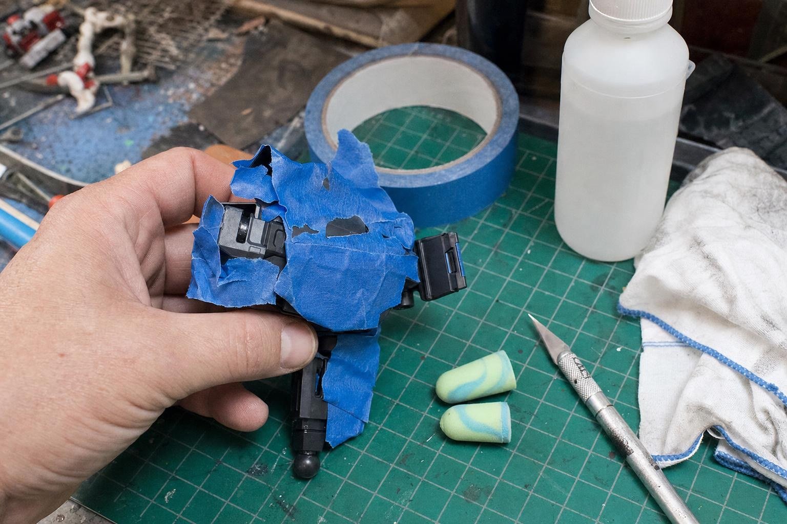 Masking tape, foam plugs, craft knife and isopropyl alcohol laid out for paint preparation