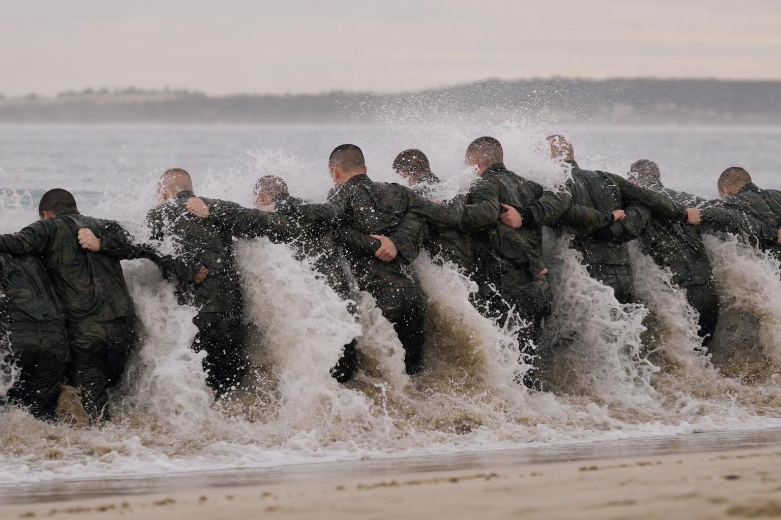 Navy SEAL candidates linking arms in the cold surf during training